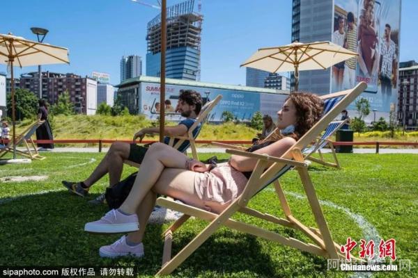 资料图：意大利米兰允许市民在公园内晒太阳，草地上画圈保持距离。图片来源：Sipaphoto