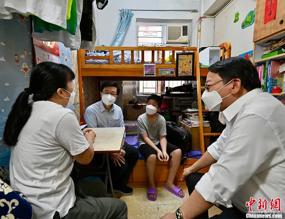 图为7月30日李家超(左二)在政务司司长陈国基(右一)陪同下来到深水埗，探访居住于劏房的基层家庭，了解其生活状况。 中新社发 香港特区政府新闻处 供图