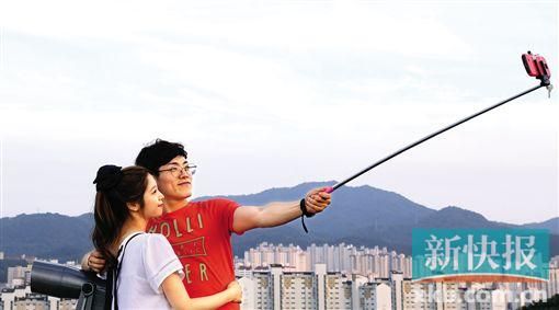 ■用自拍神器自拍已成为世界各地人们的潮流。图为7月10日,两名游客在韩国光州塔用手机自拍。 新华社发 ■用自拍神器自拍已成为世界各地人们的潮流。图为7月10日,两名游客在韩国光州塔用手机自拍。 新华社发